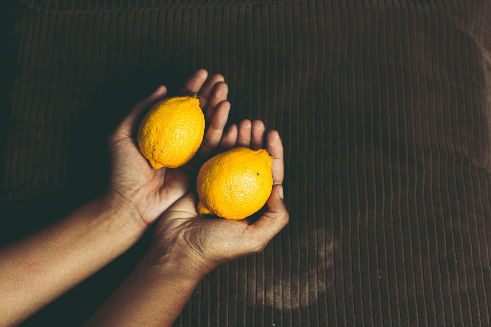 Two hands holding fresh lemons together, symbolizing new partnership and shared pleasure.