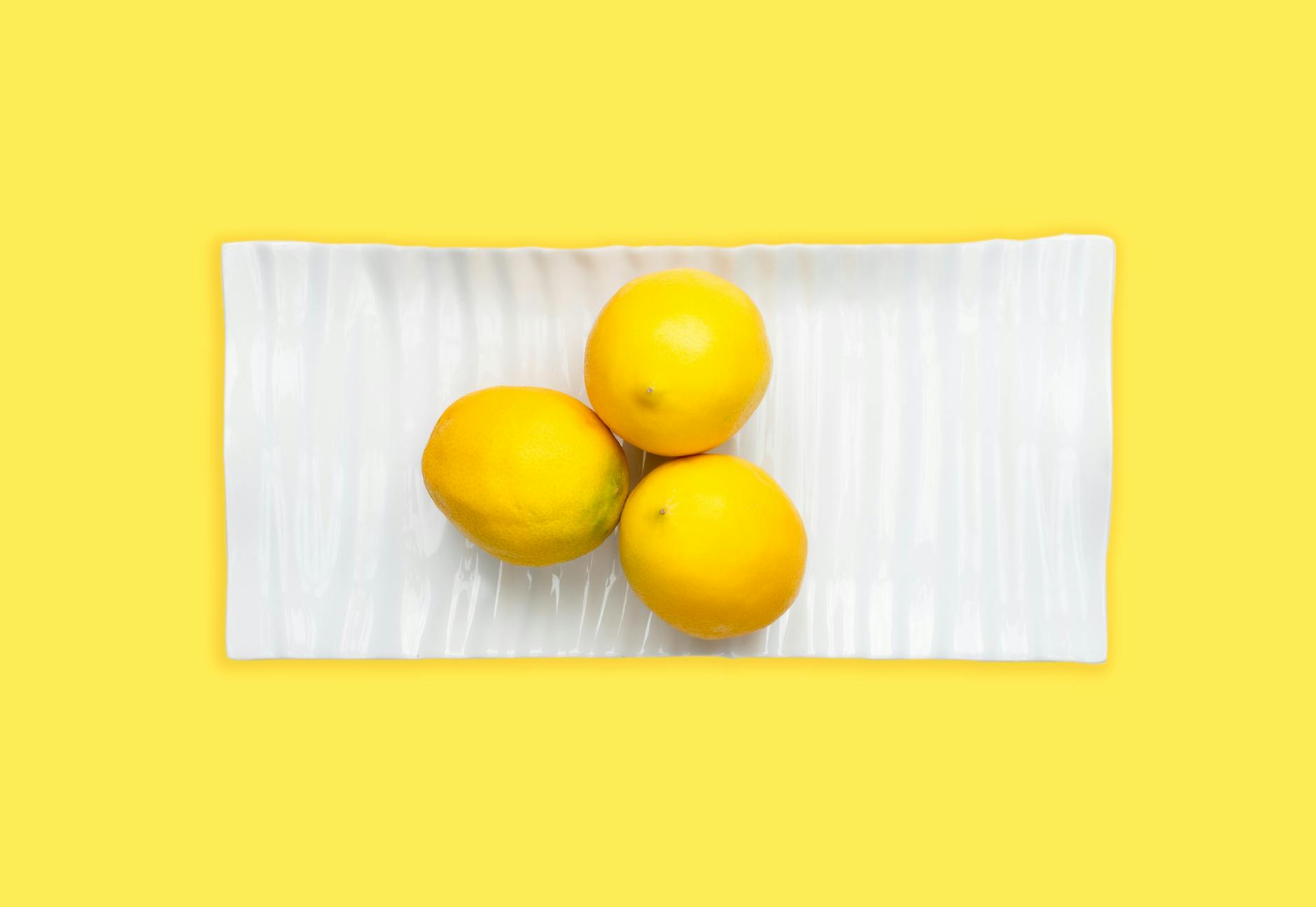 Two hands holding vibrators against a pastel background