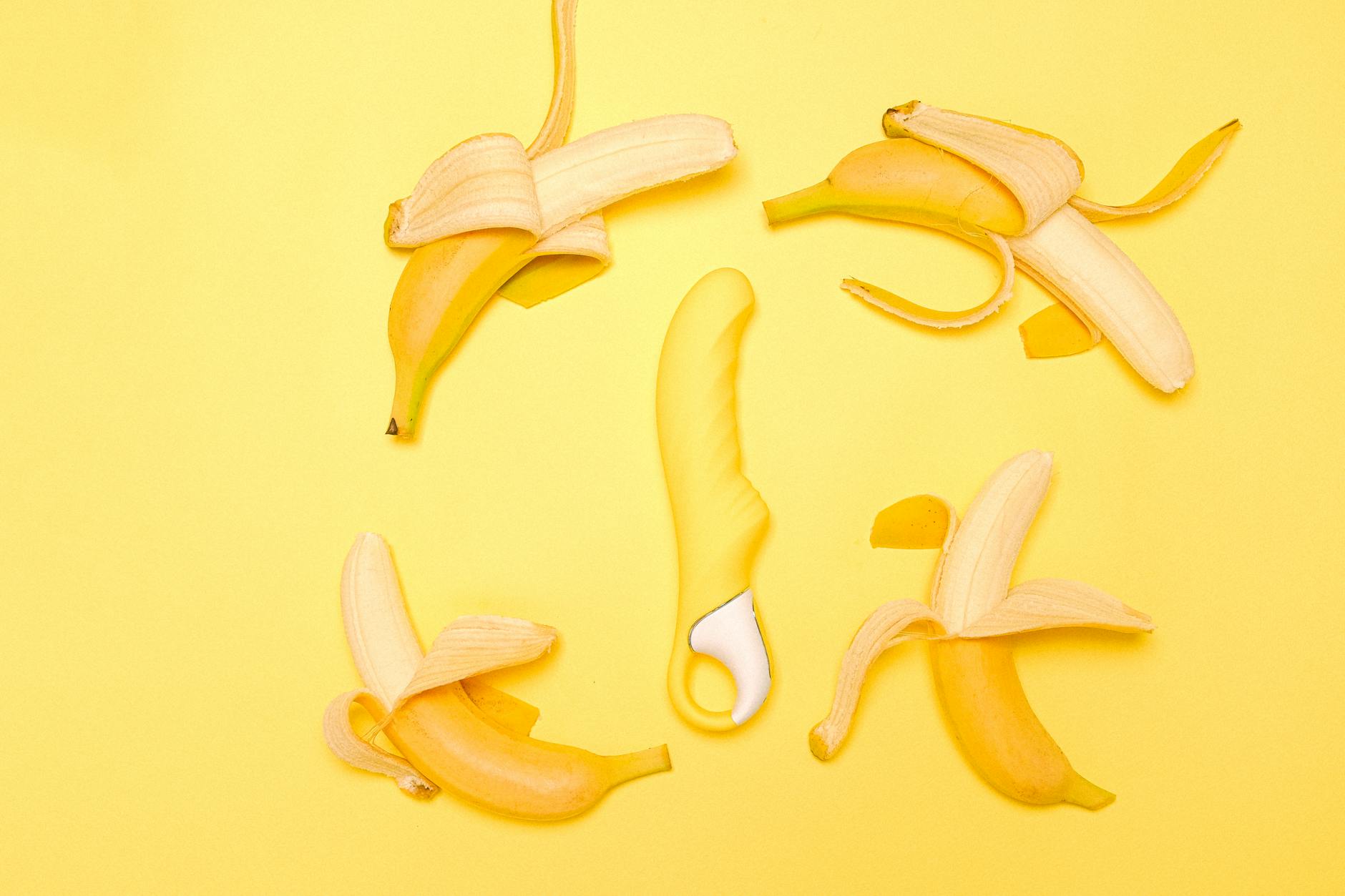 Bright yellow lemon vibrator surrounded by fresh lemons on yellow background, symbolizing restoration and sensation