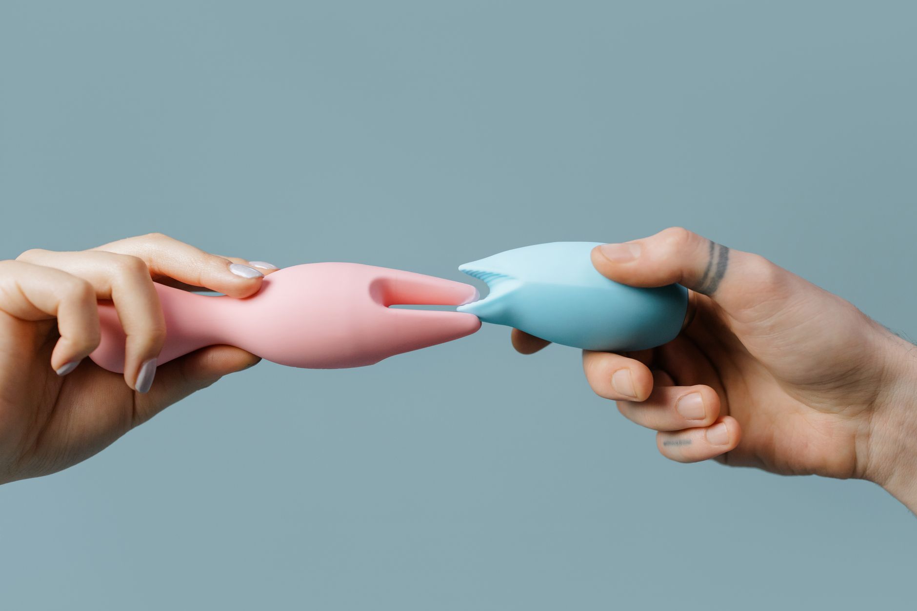 Hands holding colorful silicone pleasure toys, representing body-safe intimacy options