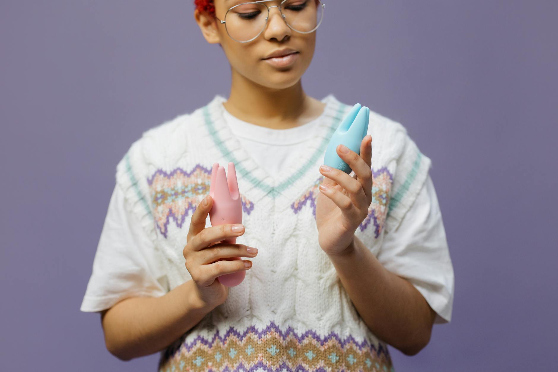 Woman holding blue and pink silicone vibrators, representing self-care and partner play options.