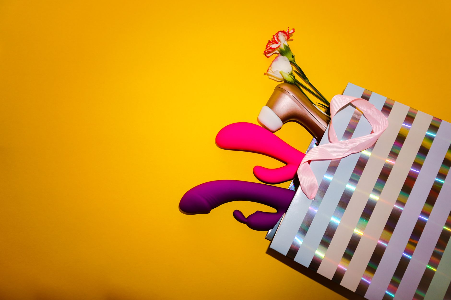 A yellow silicone vibrator surrounded by peeled bananas on a yellow background