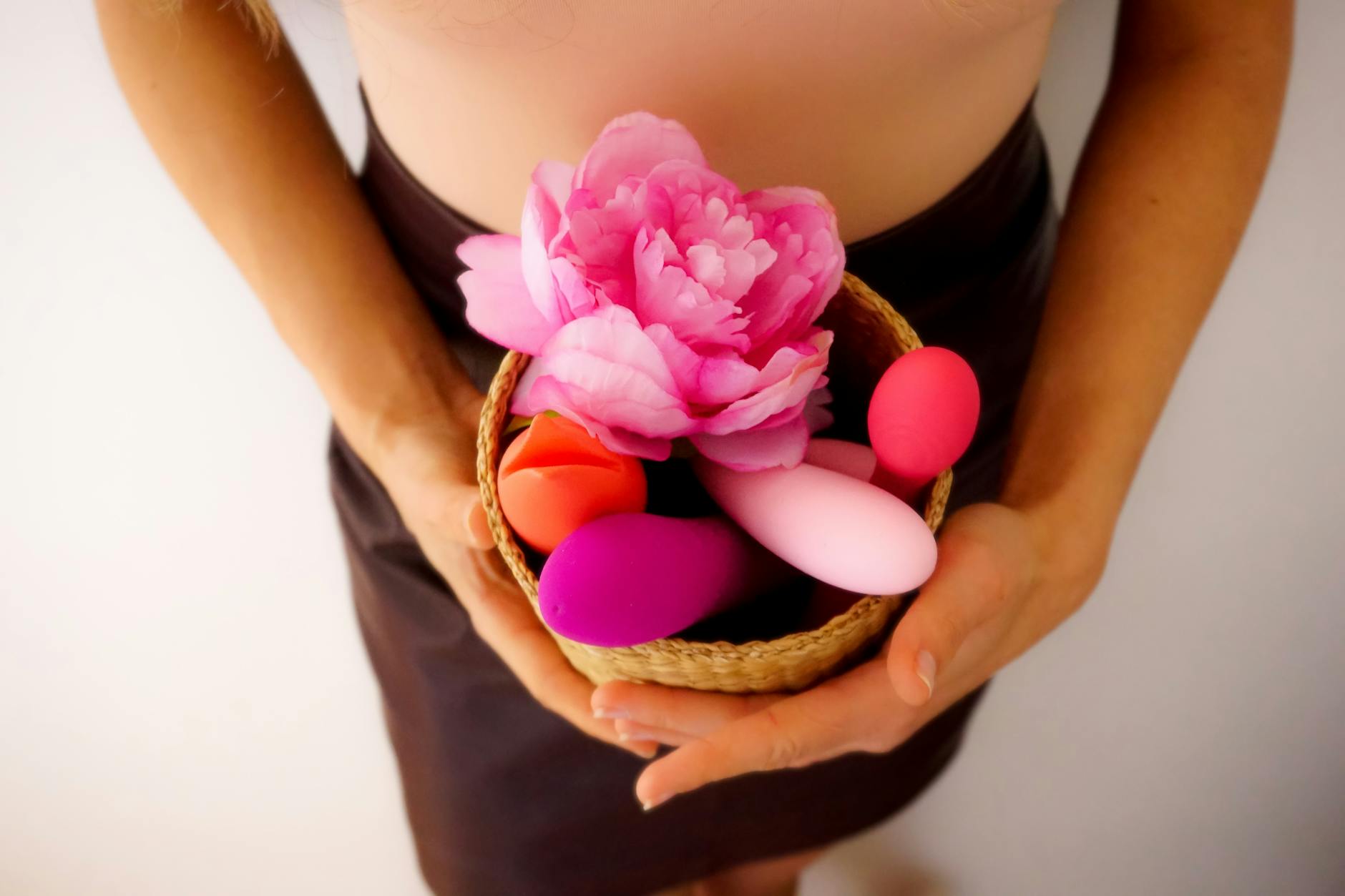 Blue vibrator surrounded by fresh flowers and citrus on yellow background