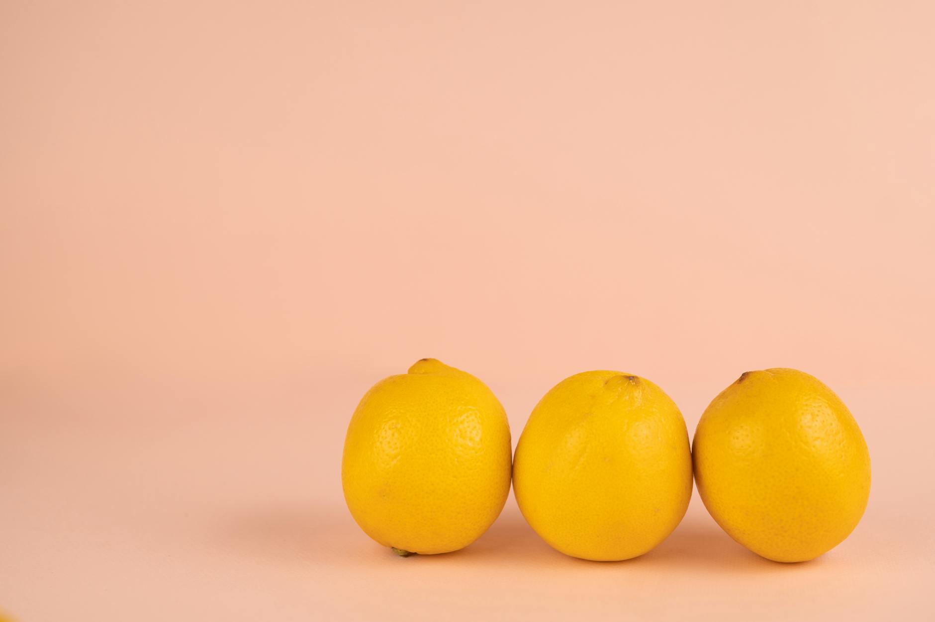 Bright yellow lemons arranged on a soft pastel surface, representing the lemon clitoral vibrator design